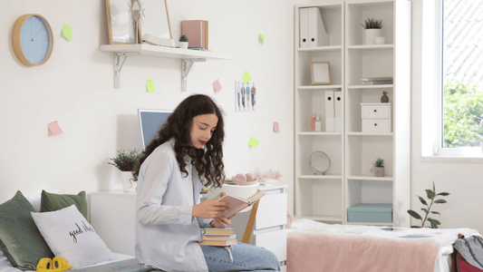 A happy pregnant woman (week 20–24) sitting on a bed journaling or reading a baby book with a soft glowing background