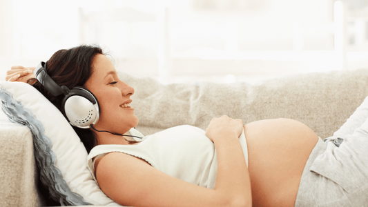 A pregnant woman sitting comfortably on a couch, surrounded by pillows, with a peaceful and relaxed expression.