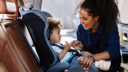 A mother strapping her child into a baby car seat