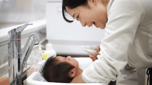 Mum gently bathing baby with a washcloth