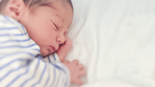 a newborn sleeping peacefully in a bassinet with no loose bedding or toys. White, calming tones work well.
