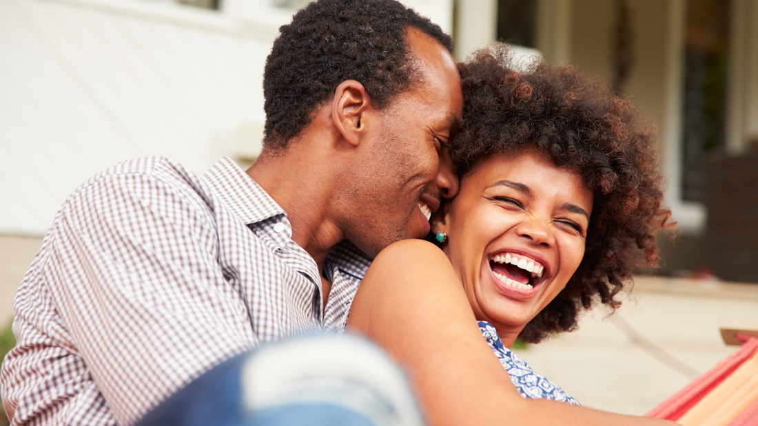 pregnant couple cuddling and laughing together at home