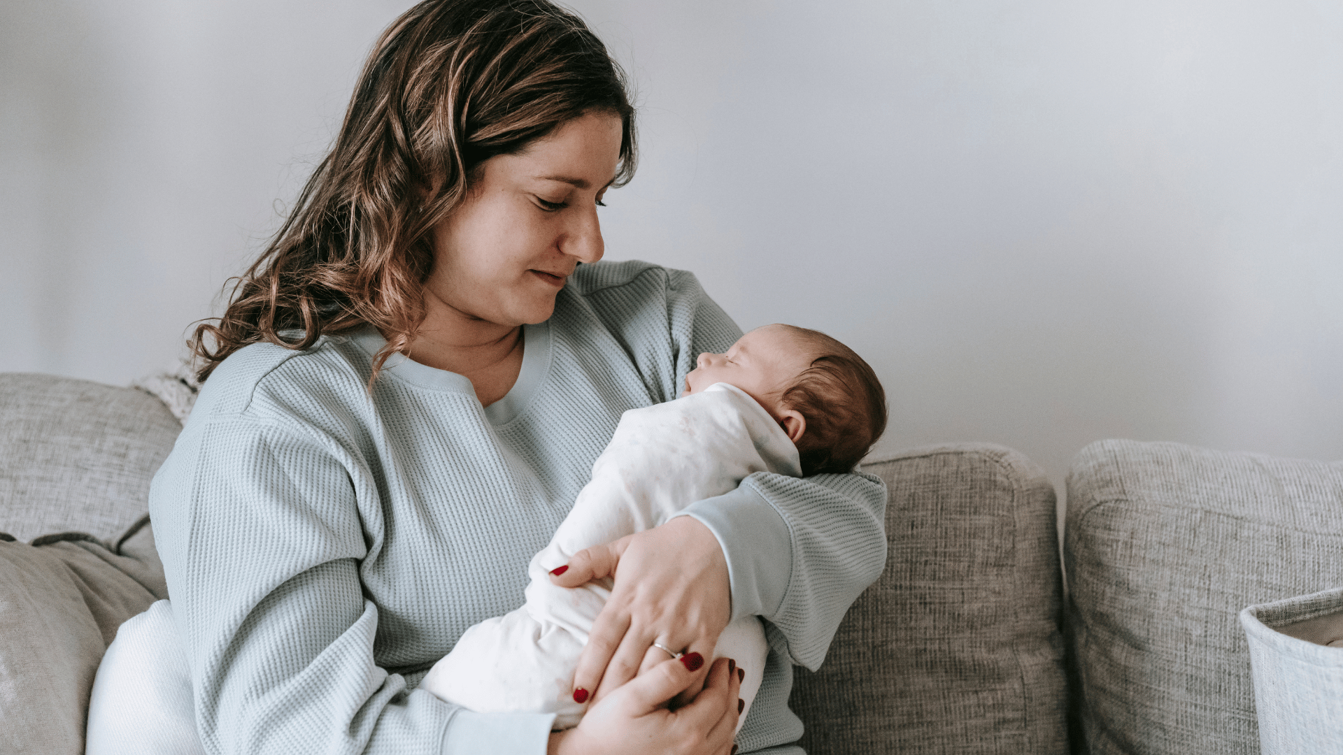 A mum in cozy loungewear holding a newborn in a typical UK living room