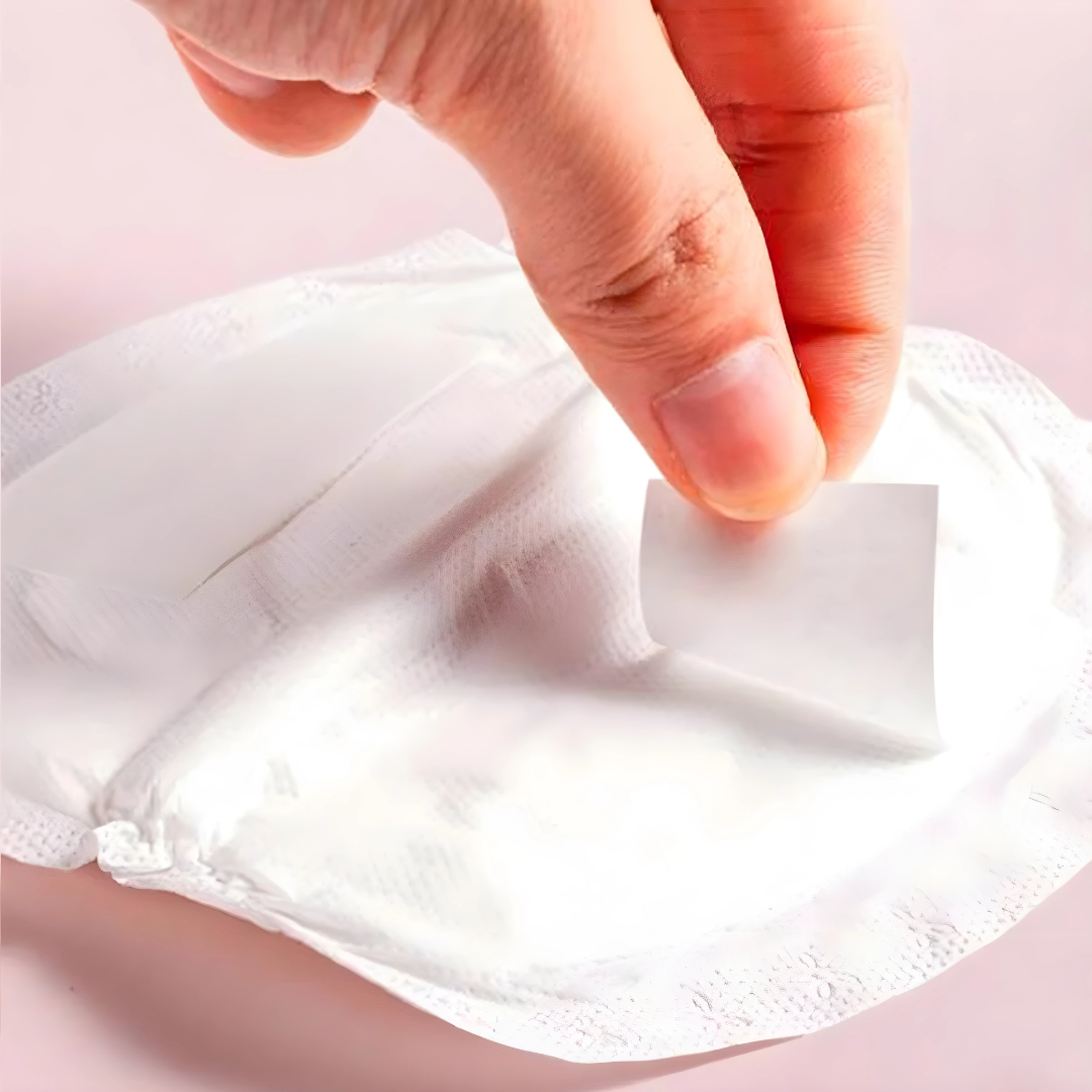 Close-up of a hand touching a white fabric pad on a pink background