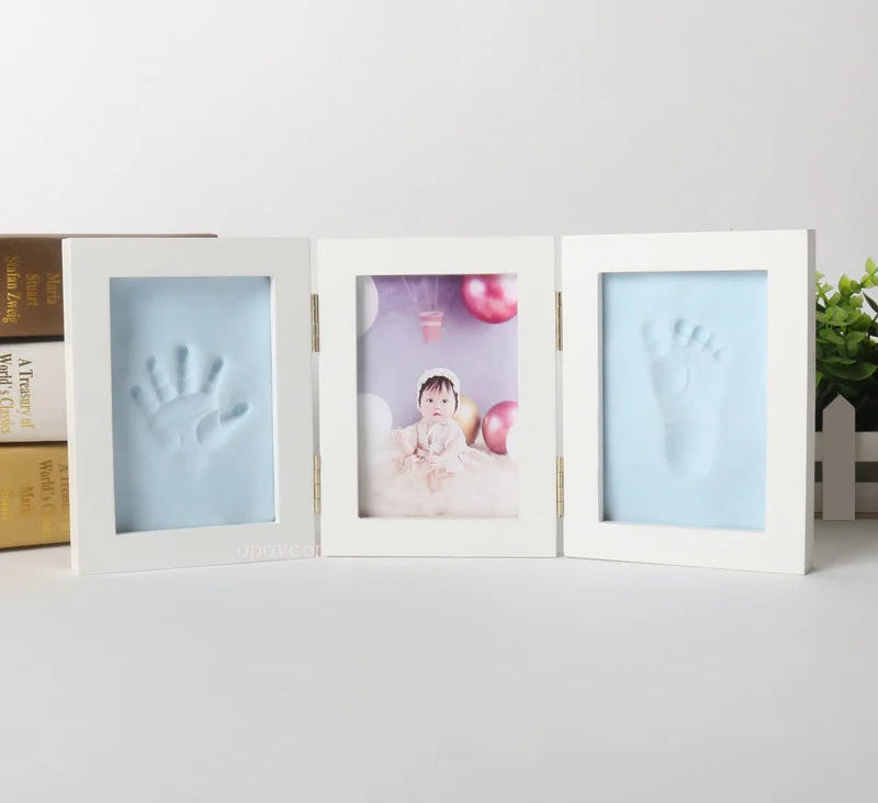 Three white photo frames with baby hand and footprints on a light gray background.