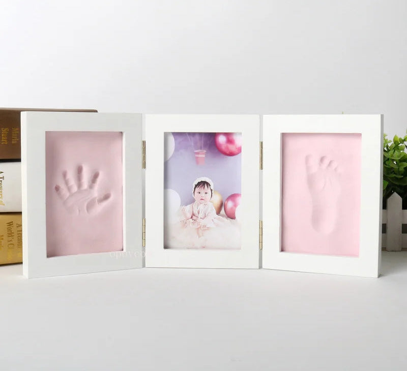 Three-section baby photo frame with pink handprint sections on a white background.