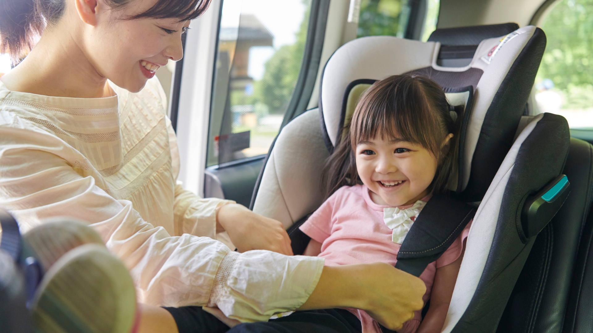 A mother strapping her daughter into her baby seat inside the car