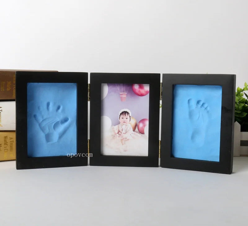 Three black photo frames with baby hand and footprints, displayed on a white surface.