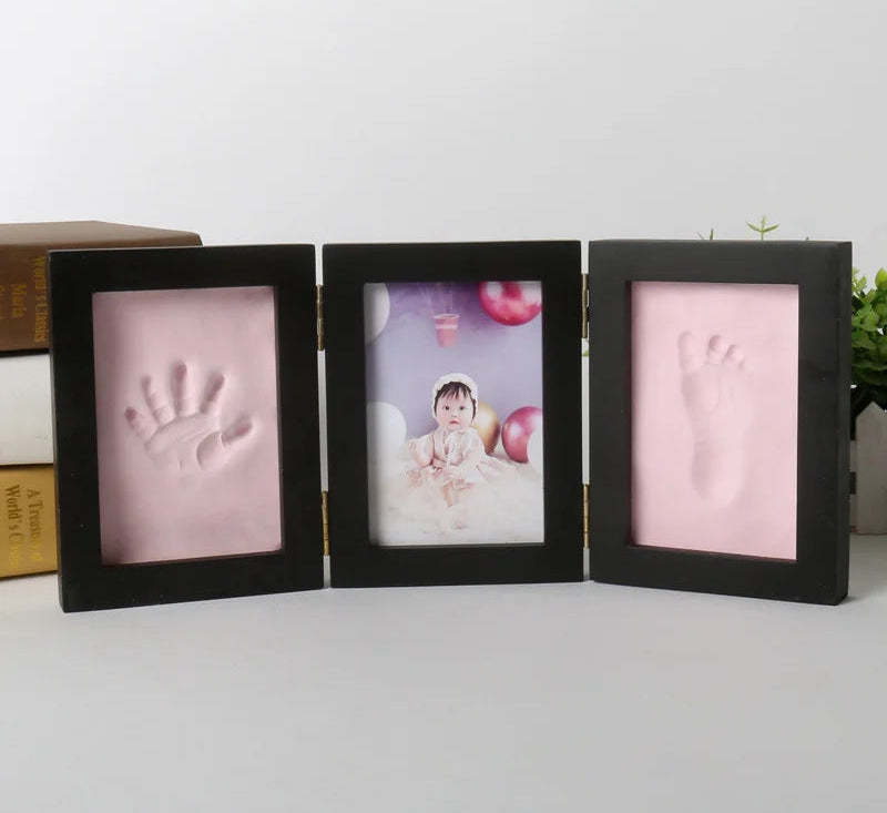 Three black photo frames with baby hand and footprints on a light background.