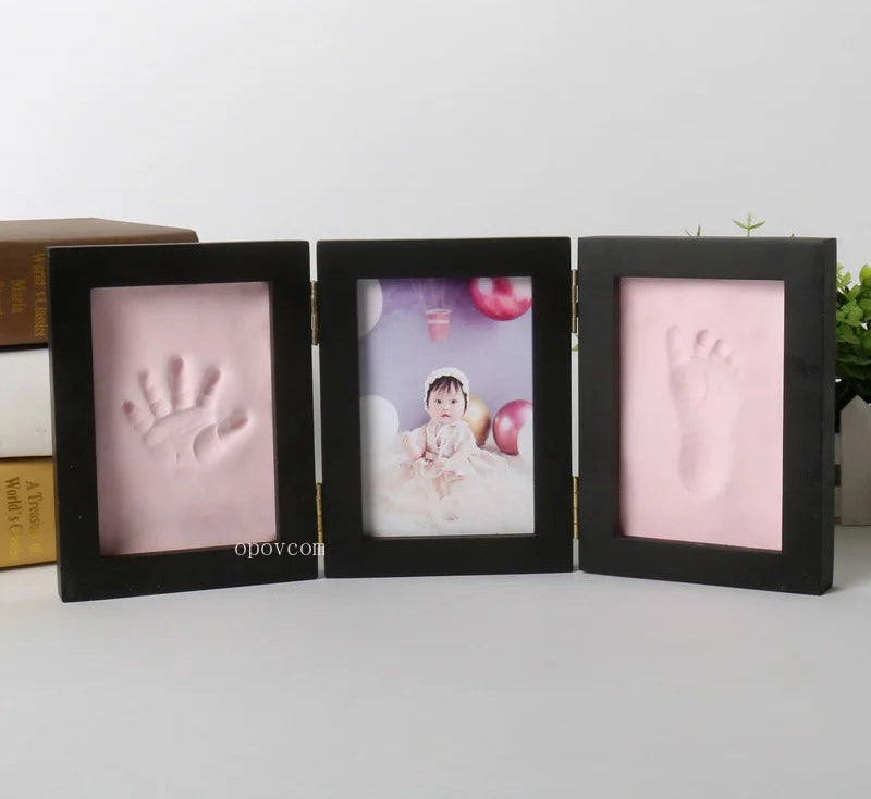 Three black photo frames with baby hand and footprints on a light background.