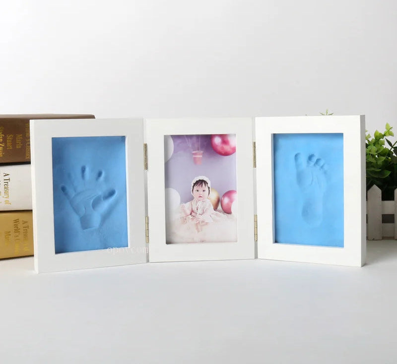 Three white photo frames with blue handprint and footprint on a light gray background.