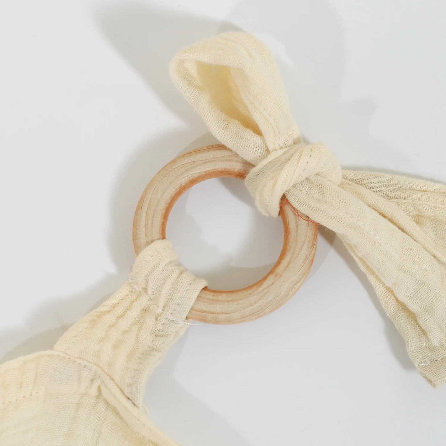 Wooden teething ring with beige fabric straps on a white background