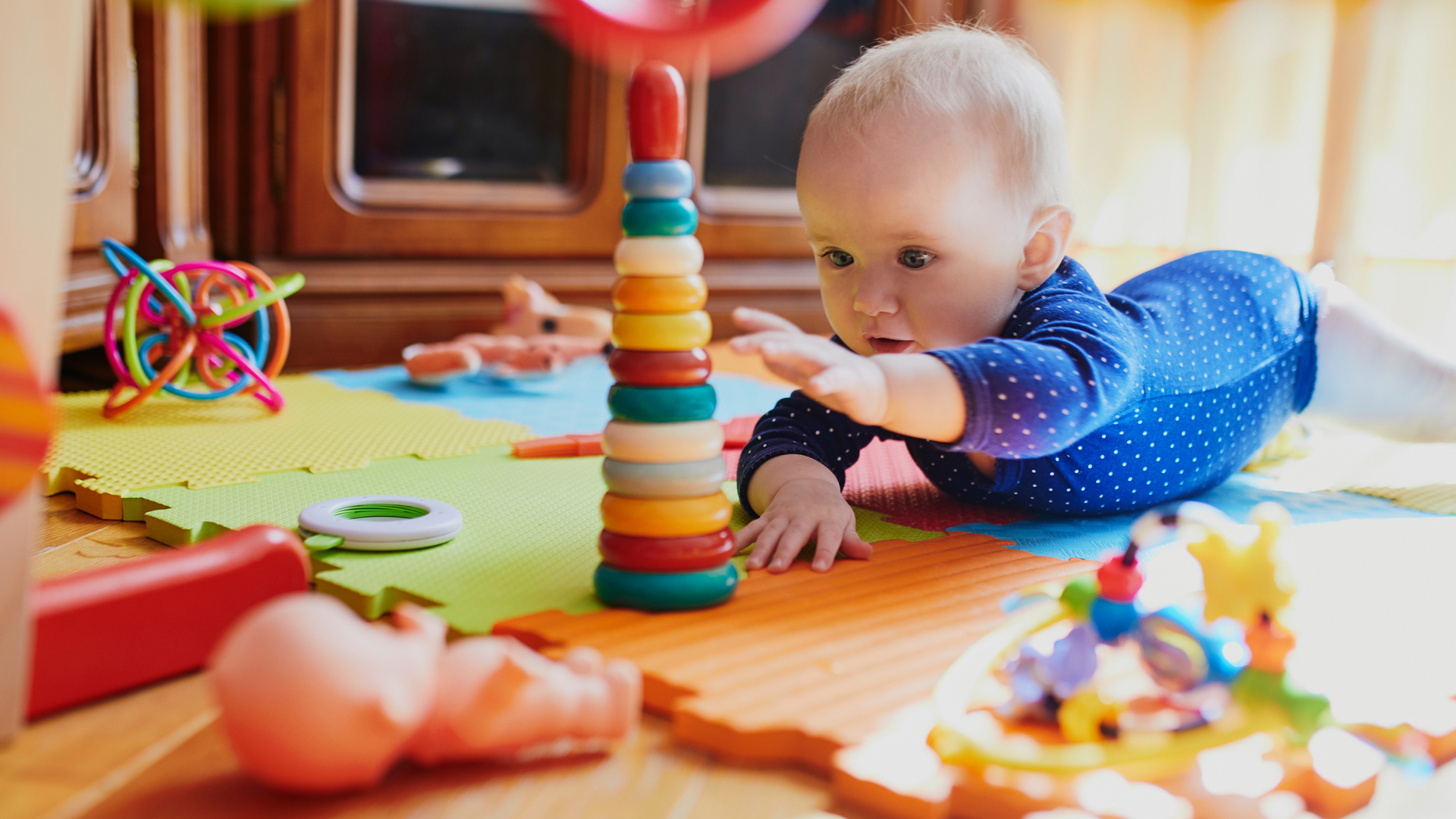 Baby playing with colorful toys on a mat