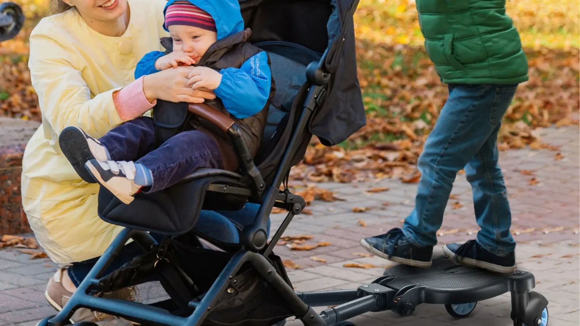 Child in a stroller with a person holding them, walking outdoors on a leafy path.
