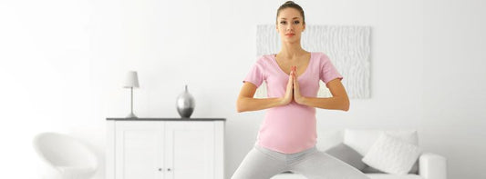 A pregnant woman in a yoga pose in a tranquil, well-lit room.