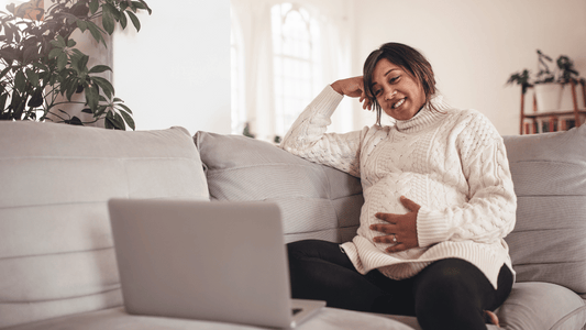 A cheerful, pregnant woman in a cosy, well-lit living room, wearing stylish maternity leggings and a comfortable top