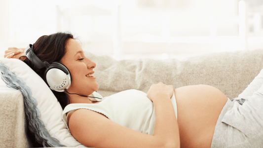 A pregnant woman sitting comfortably on a couch, surrounded by pillows, with a peaceful and relaxed expression.