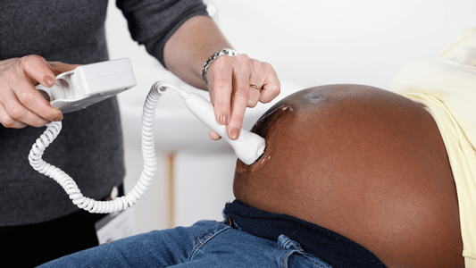 pregnant woman using a Doppler device with partner listening