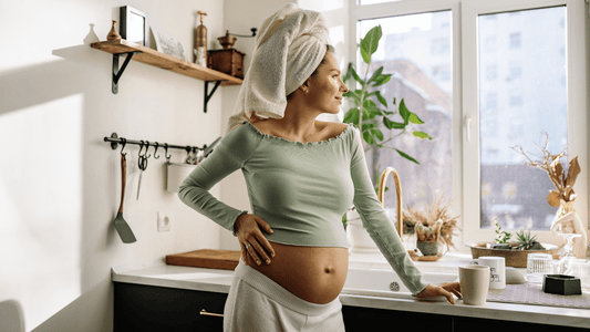 Pregnant woman in profile, cradling her belly, with soft pastel tones and subtle floral accents.