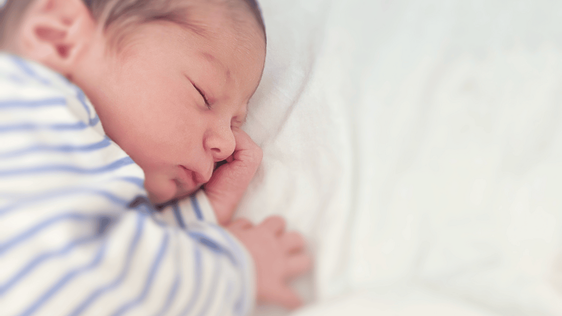 a newborn sleeping peacefully in a bassinet with no loose bedding or toys. White, calming tones work well.