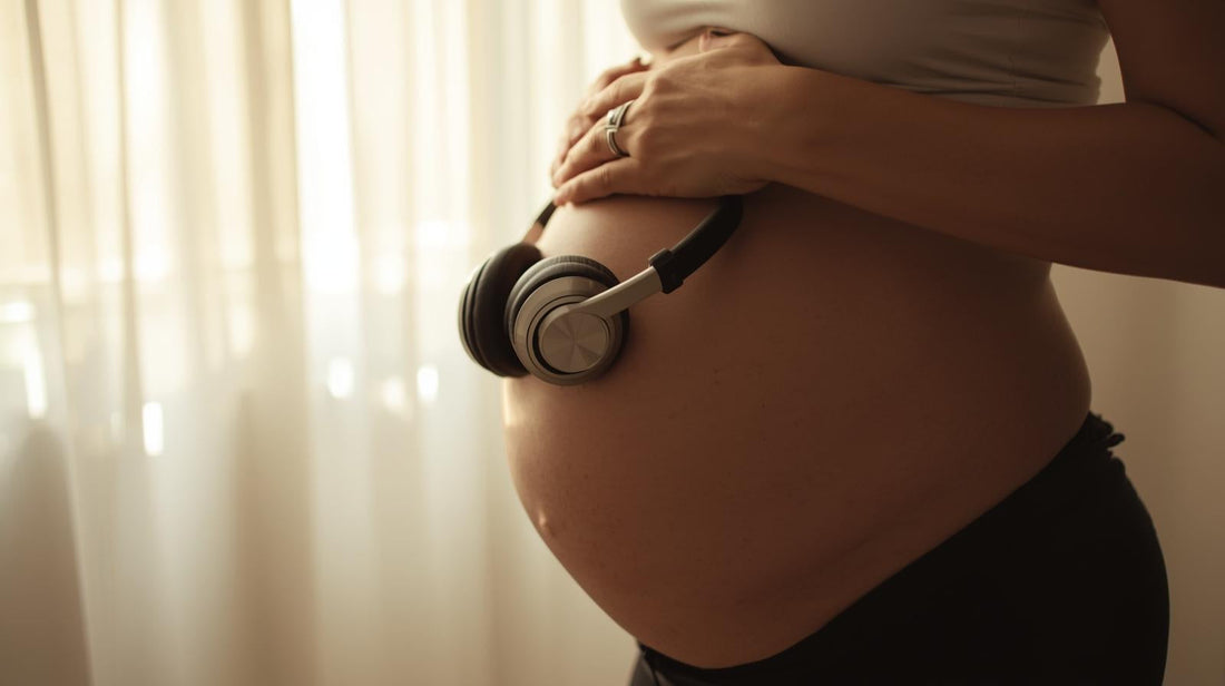 pregnant woman with headphones on belly in soft light