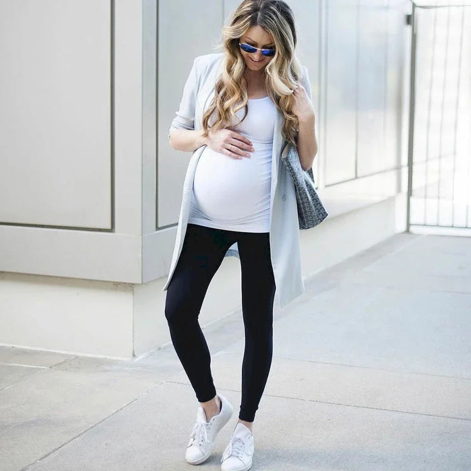 Happy pregnant woman in fitted maternity leggings and top.