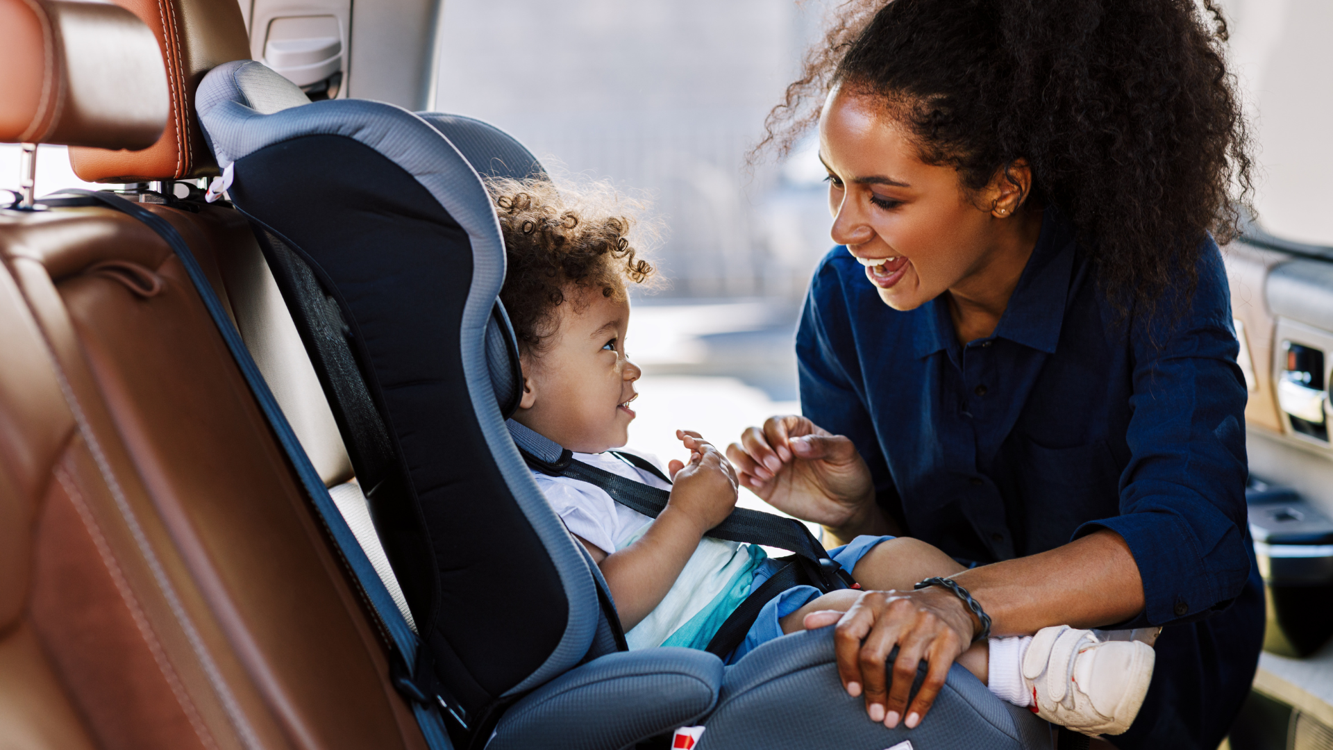 A mother strapping her son into his car seat