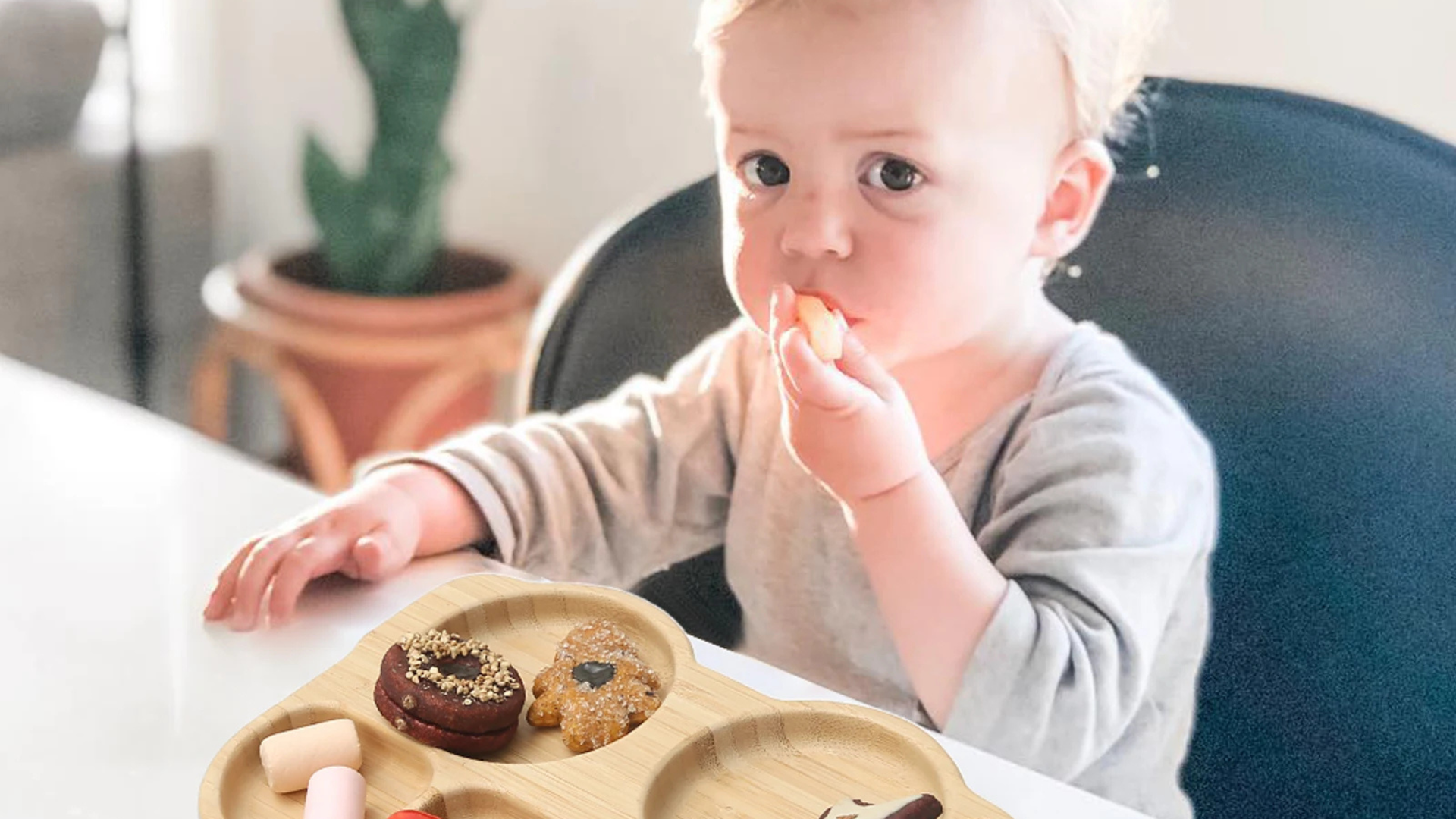 Child sitting at a table with a plate of cookies and donuts, indoors.