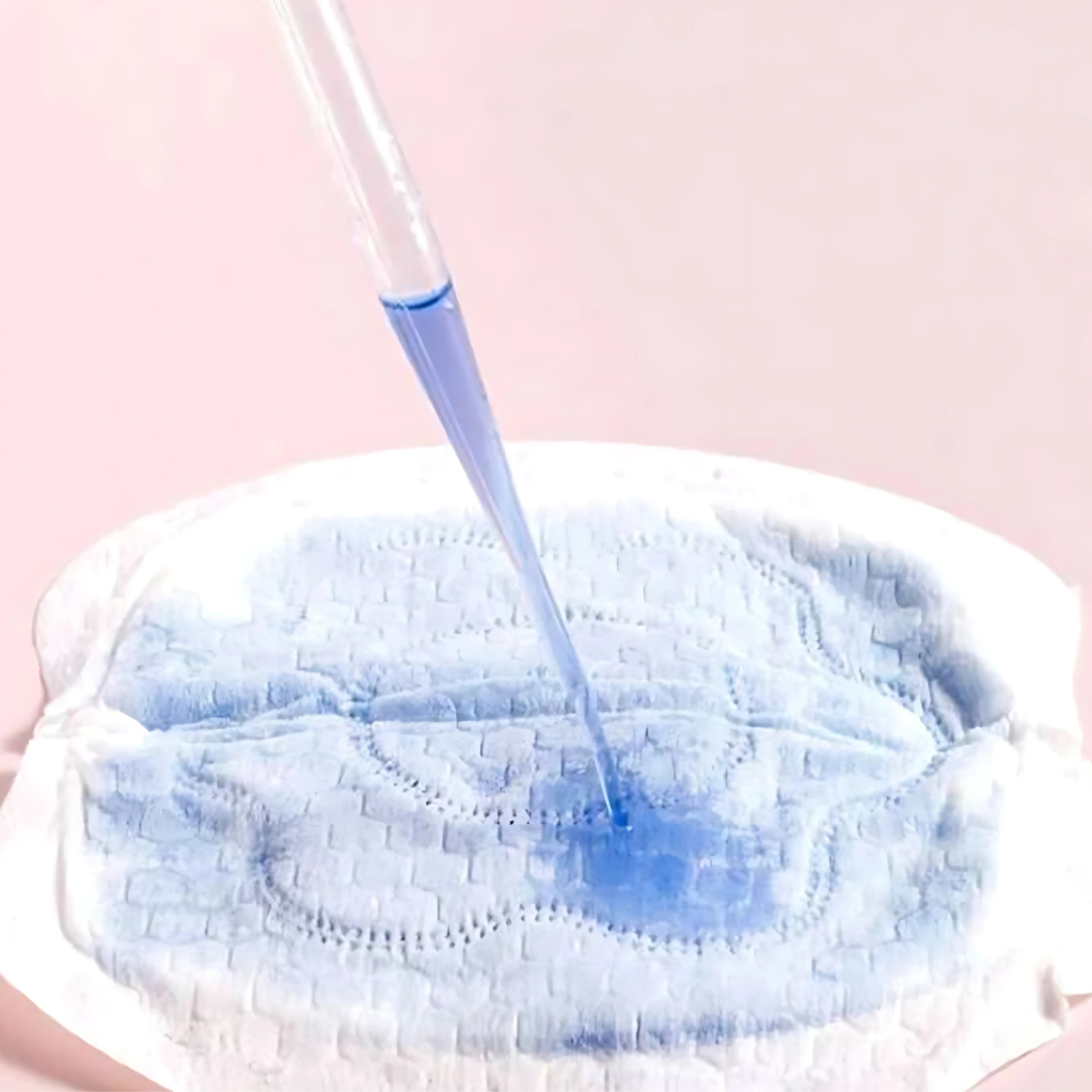 Blue liquid is being poured onto a nursing pad with a pink background