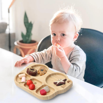 Child eating from a wooden tray with compartments on a dining table.