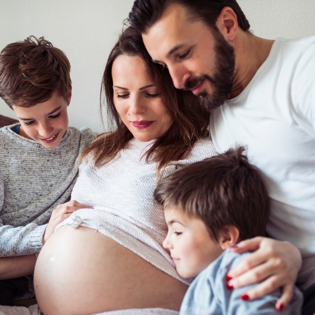 Family listening to a pregnant woman's belly