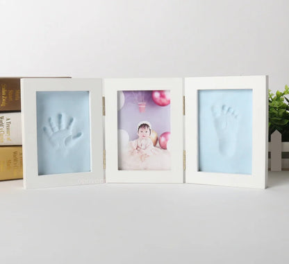 Three white photo frames with baby hand and footprints on a light gray background.