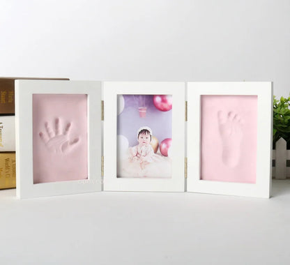 Three-section baby photo frame with pink handprint sections on a white background.