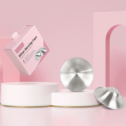 Silver nursing cups with packaging on a pink background