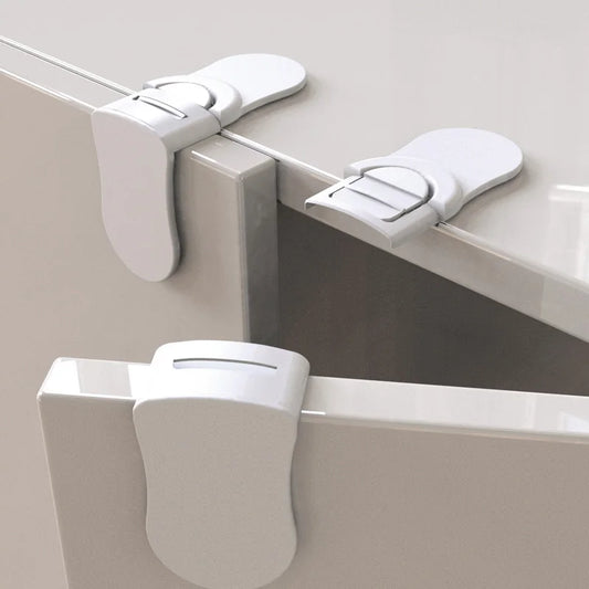 Three white cabinet locks on a gray surface
