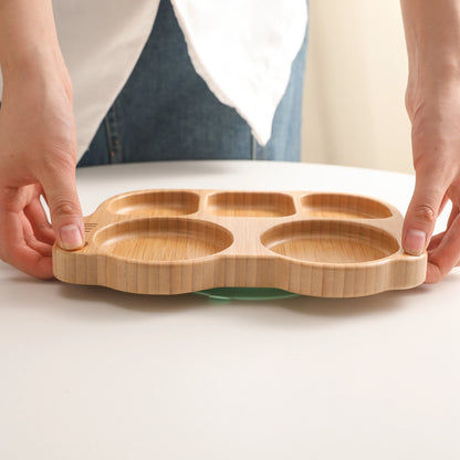 Wooden baby plate with compartments held by hands on a light background