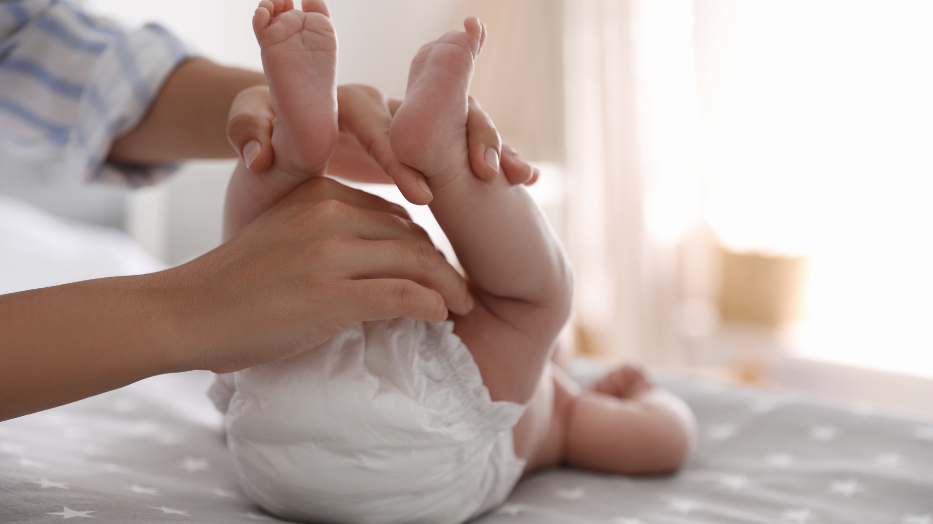 Baby's feet being held by an adult on a bed