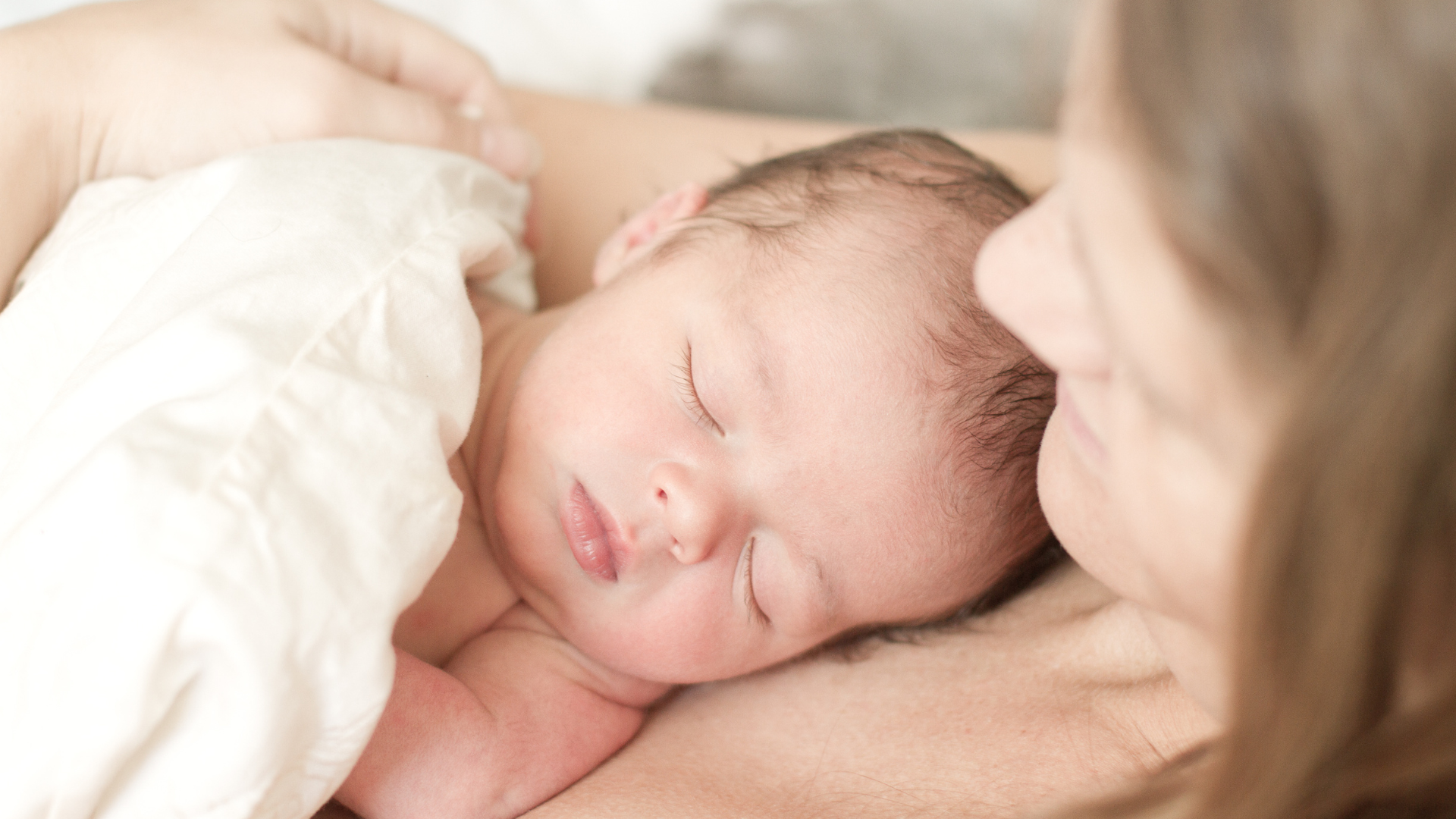 Newborn baby sleeping peacefully on a woman's chest with a blurred background