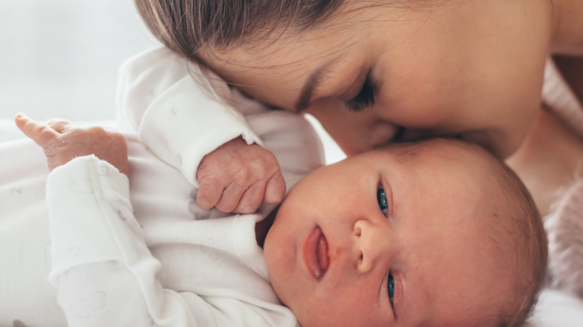 Newborn baby wrapped in white fabric with a blurred background