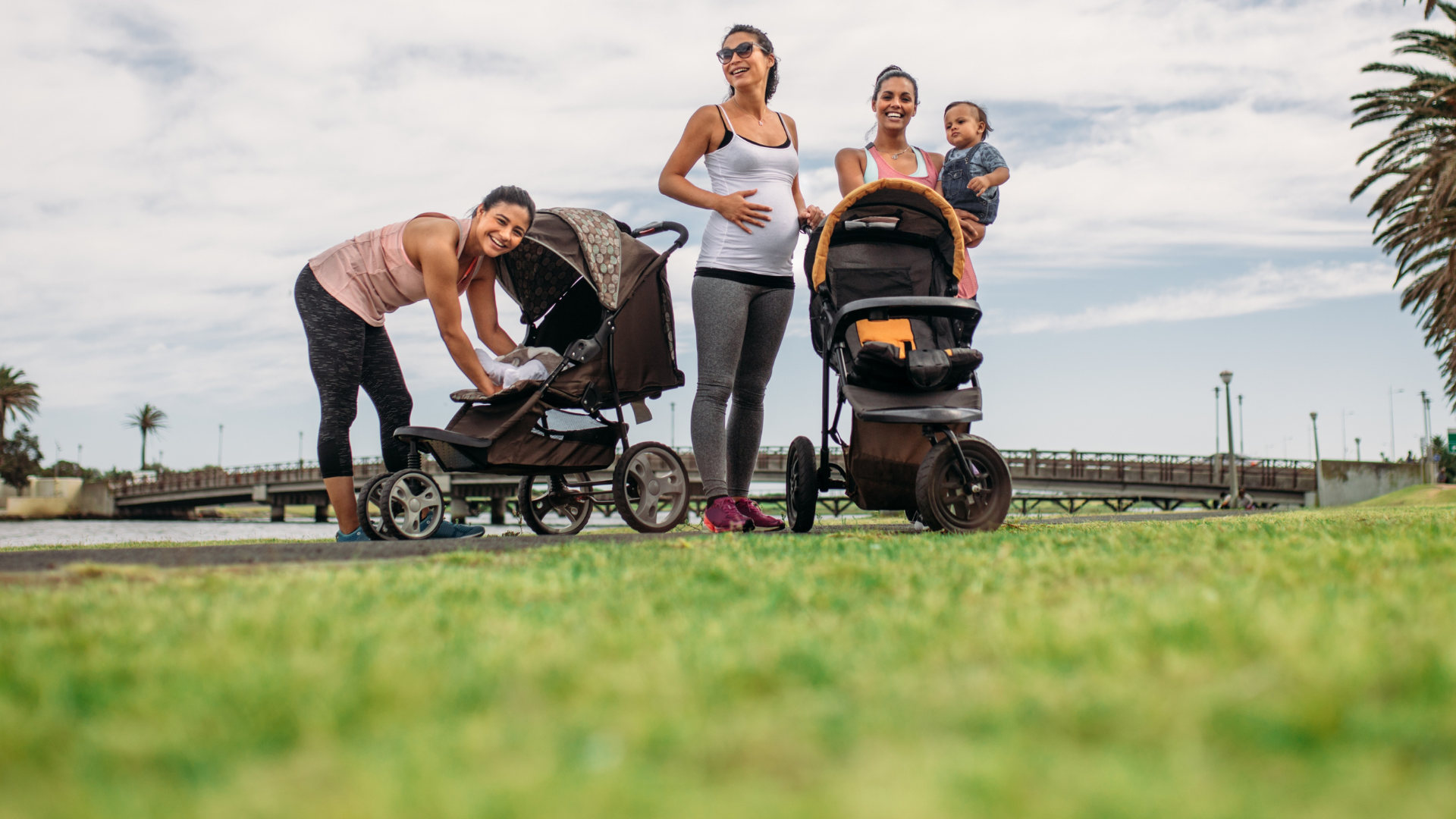 Two women with strollers in a park setting